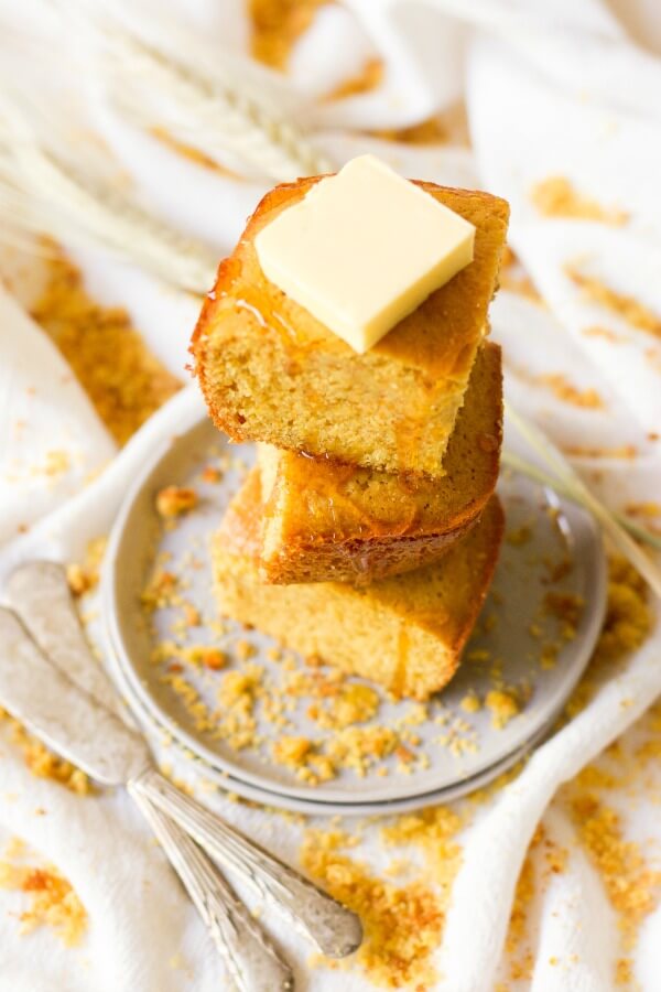 Stack of cornbread slices with butter and honey drizzle.