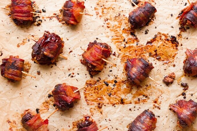 Bacon wrapped dates on baking sheet.