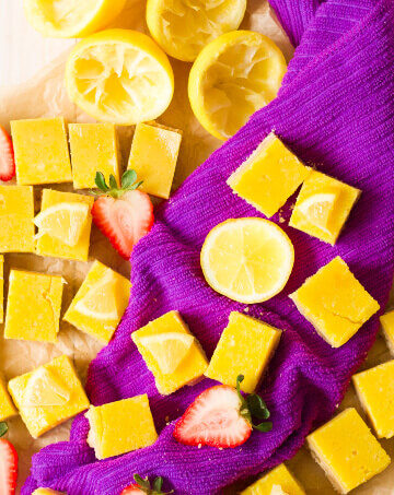 Homemade lemon squares with fresh lemon and strawberries.