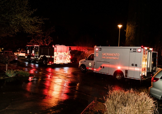 A firetruck and fire department ambulance with lights flashing on a rainy night.