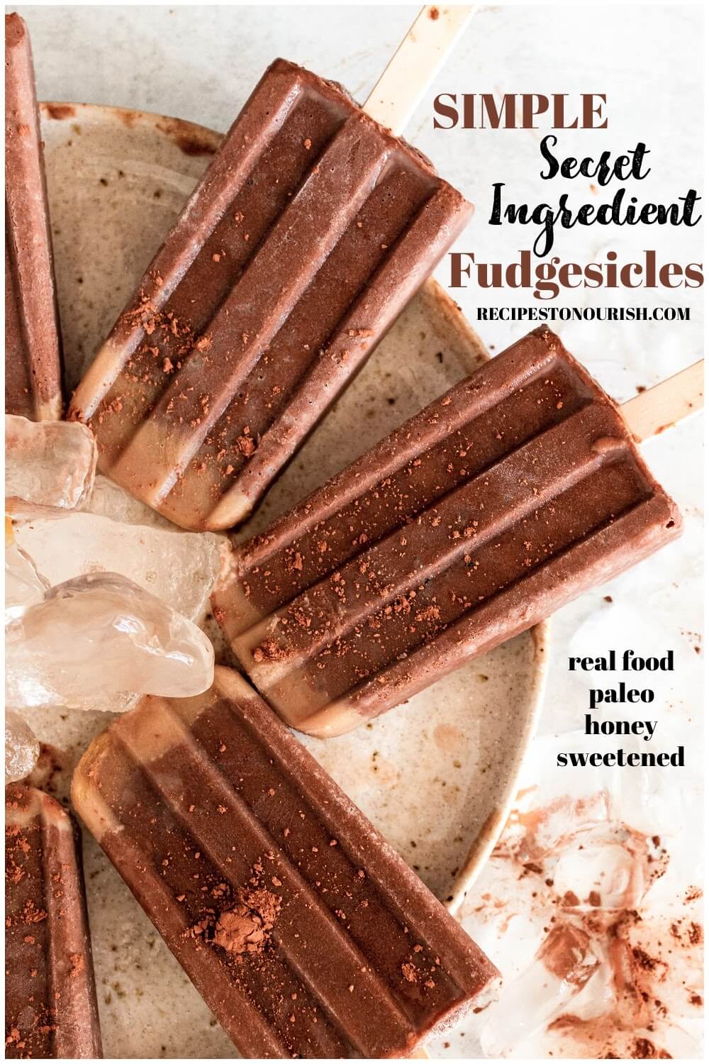Fudgesicle popsicles dusted with cocoa powder sitting on a plate with ice, with the text Simple Secret Ingredient Fudgesicles, real food, paleo, honey sweetened.