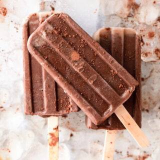 Several fudgesicle popsicles dusted with cocoa powder sitting on top of ice.