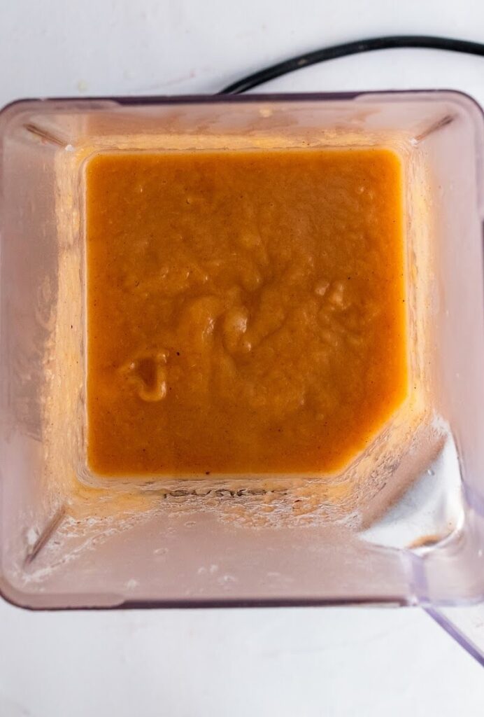 An overhead view of a blender filled with homemade pureed cinnamon applesauce.