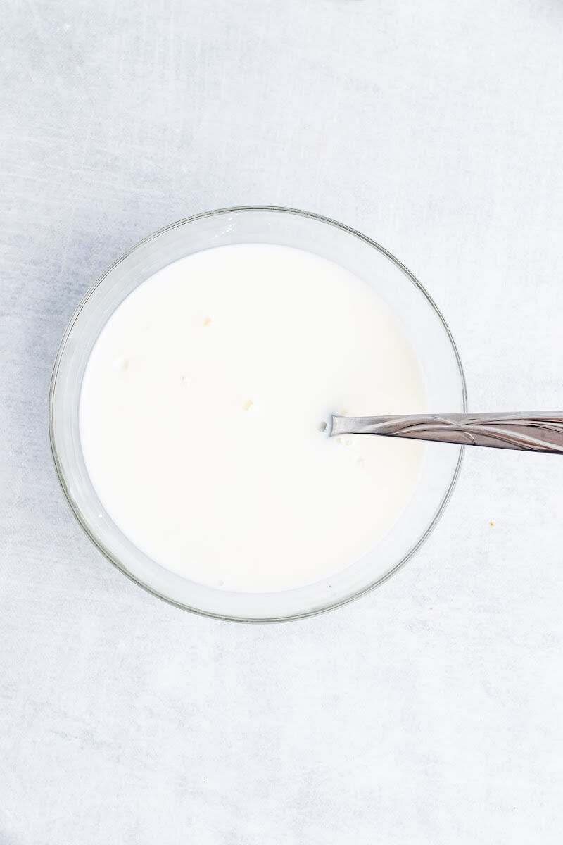 Bowl full of mixed milk and arrowroot powder with a fork mixing it.