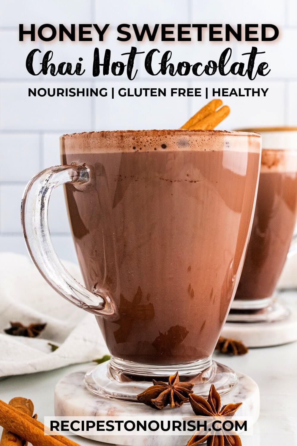 Two glass mugs filled with hot chocolate and garnished with cinnamon sticks, sitting on marble coasters with dried star anise pods sitting around them and text that says Honey Sweetened Chai Hot Chocolate nourishing gluten free healthy.