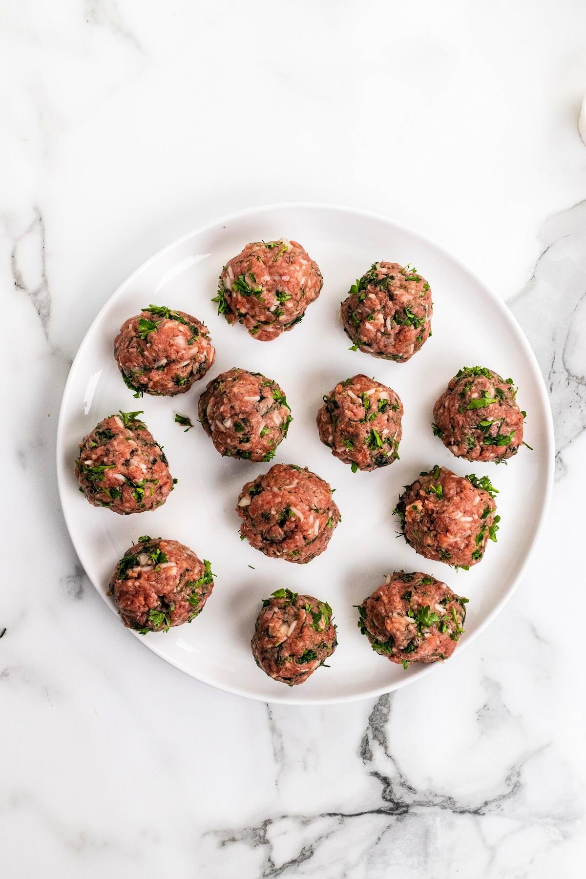 Plate with 12 raw herb-filled meatballs.