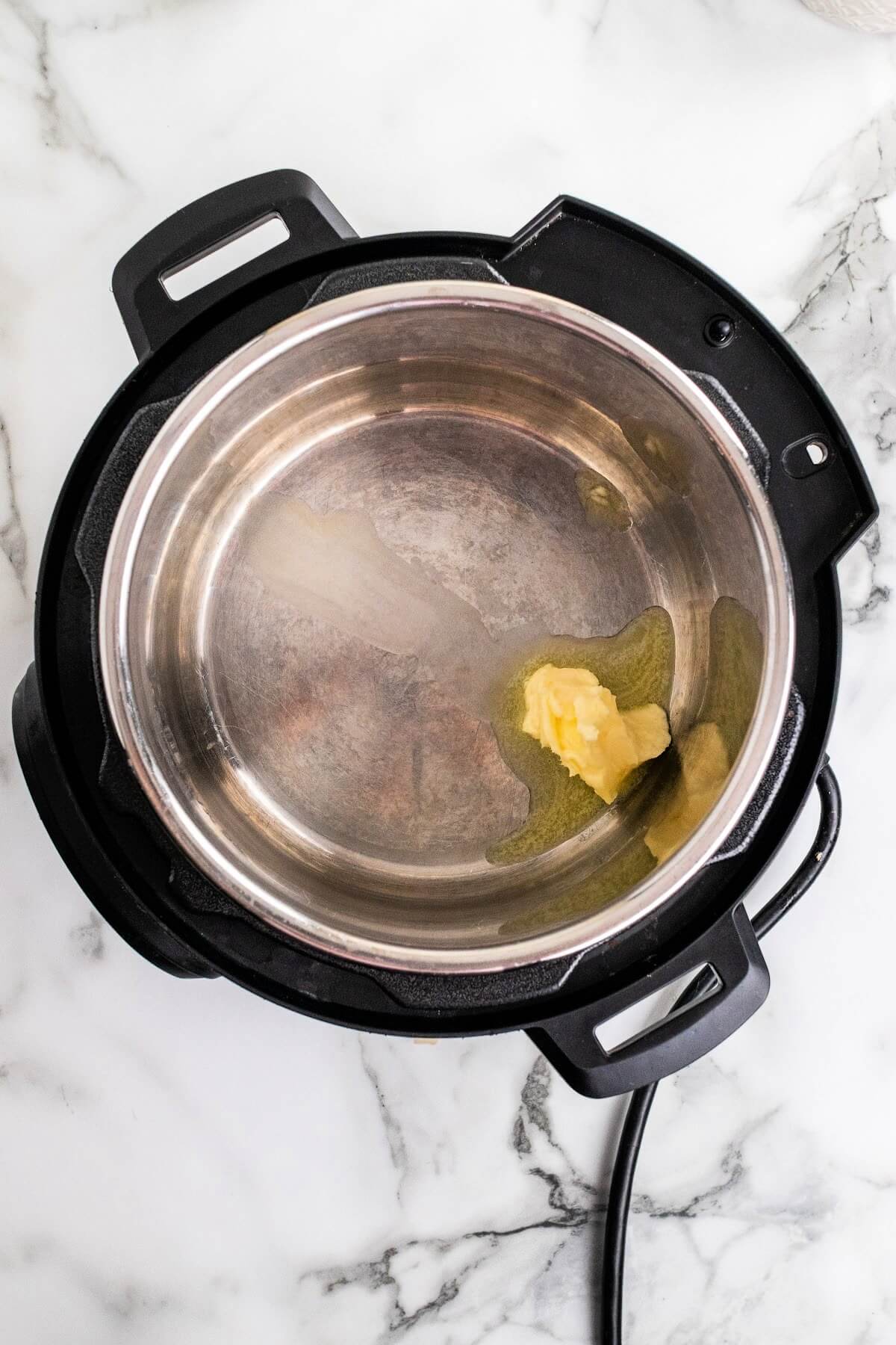 Overhead shot of an Instant Pot with butter starting to melt.
