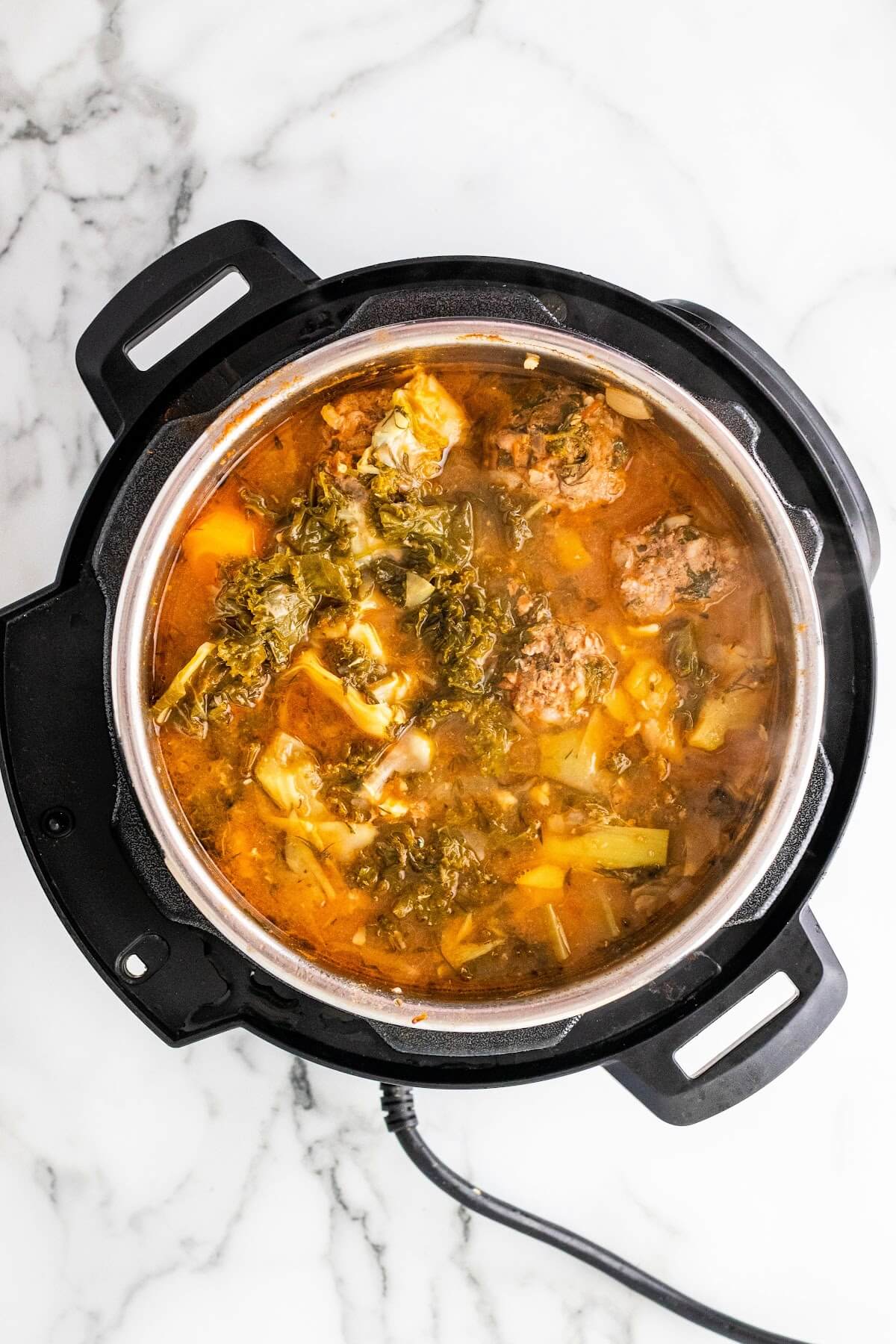 Overhead shot of an Instant Pot with a cooked broth soup with vegetables and meatballs.