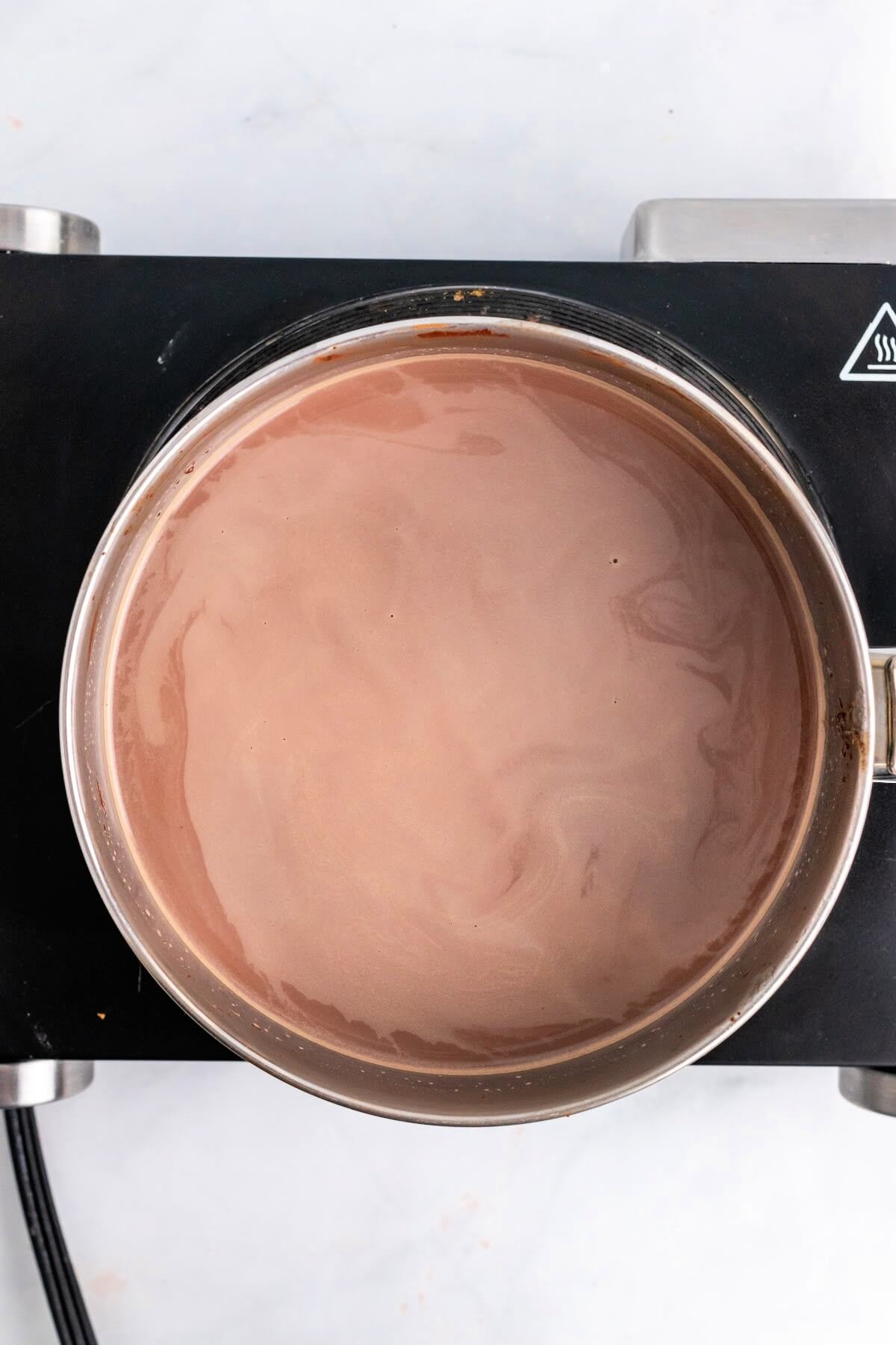 Saucepan filled with hot chocolate sitting on top of a stovetop.