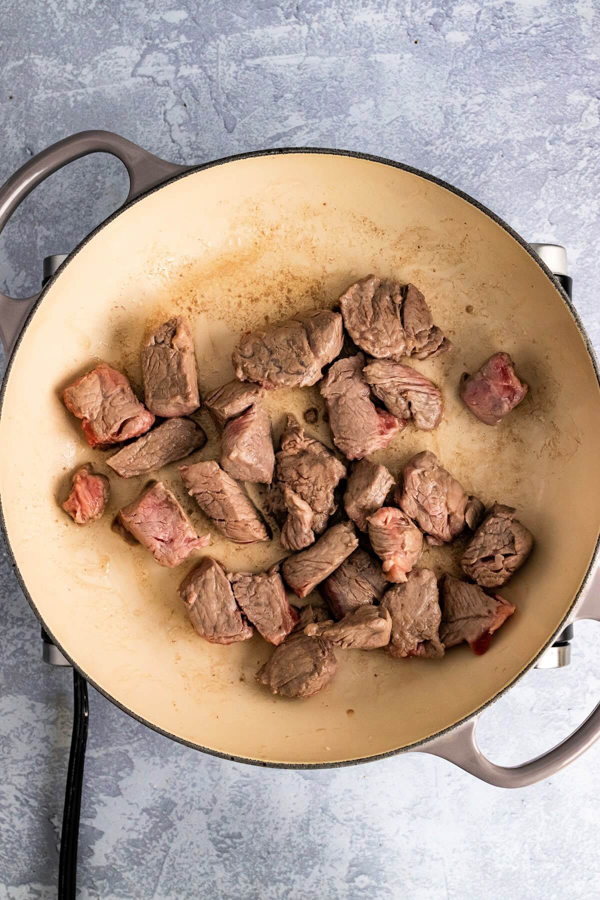 Saute pan filled with chunks of stew meat starting to be browned.