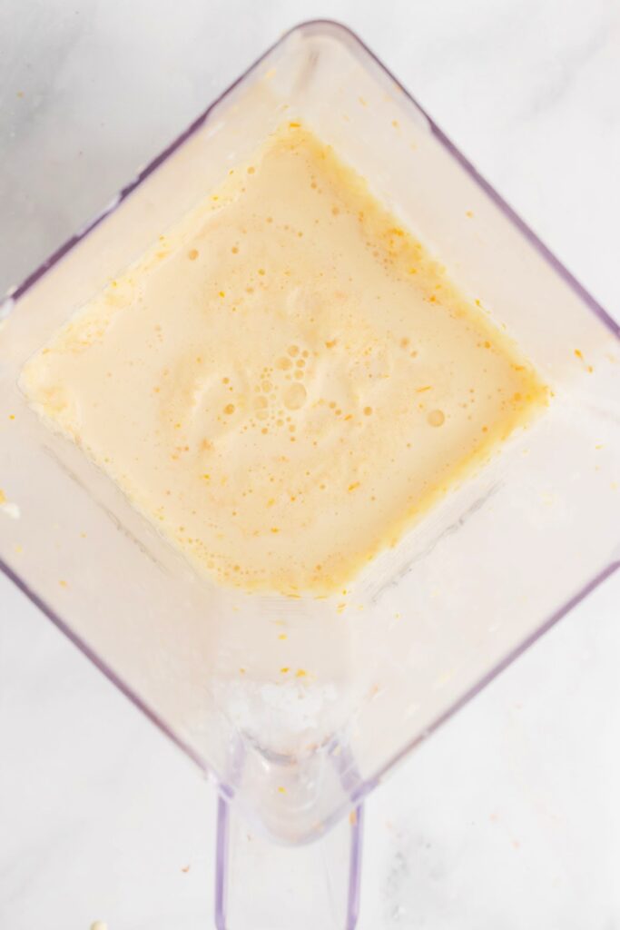 Creamy orange juice smoothie inside a blender.
