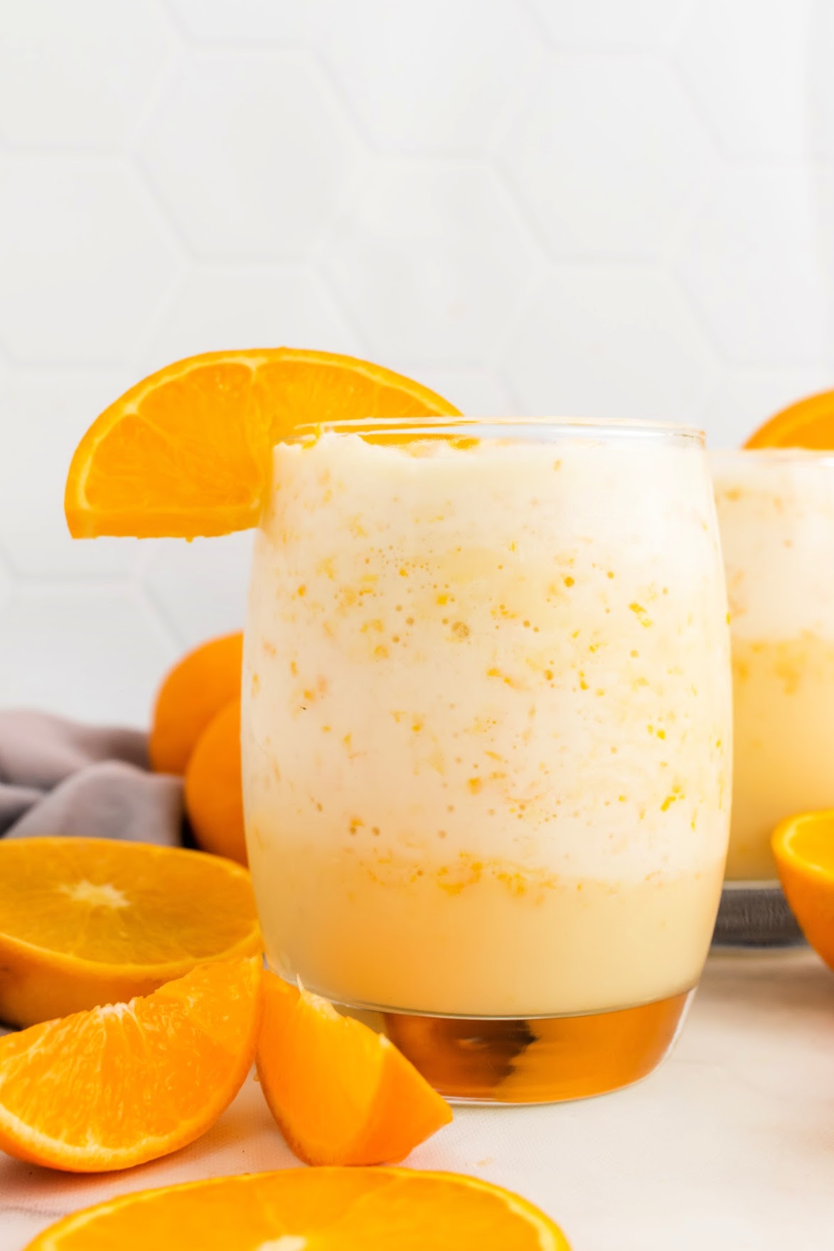 Creamy orange smoothie in a glass with fresh orange slices.